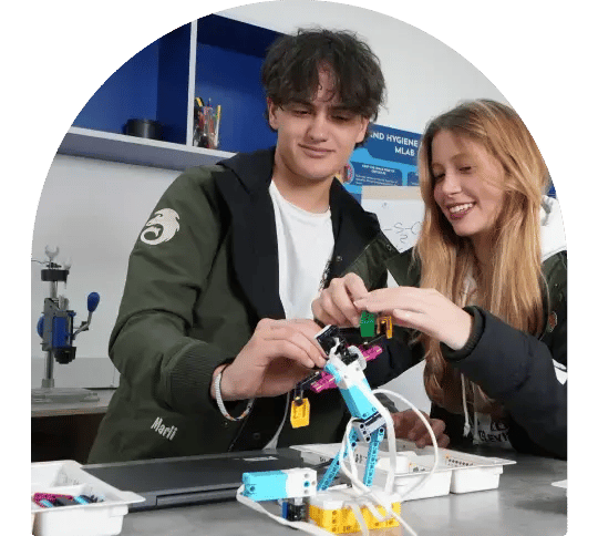 Dos jóvenes estudiantes, un hombre y una mujer, trabajando en equipo para ensamblar un prototipo de robótica en el aula. Dos jóvenes estudiantes, un hombre y una mujer, trabajando en equipo para ensamblar un prototipo de robótica en el aula.