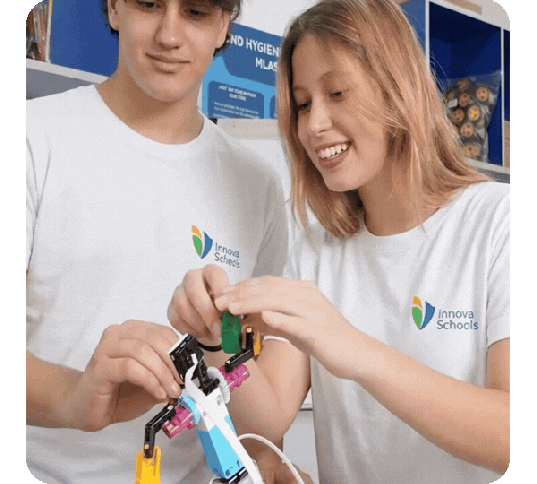 Dos jóvenes estudiantes, un hombre y una mujer, trabajando en equipo para ensamblar un prototipo de robótica en el aula.