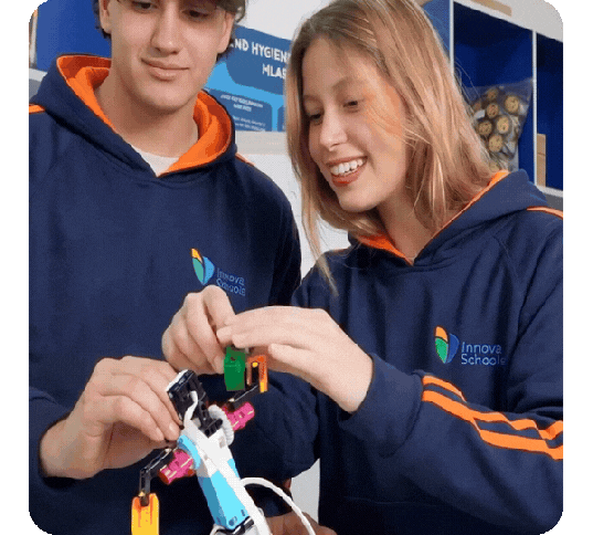 Dos jóvenes estudiantes, un hombre y una mujer, trabajando en equipo para ensamblar un prototipo de robótica en el aula.